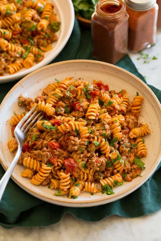 _*Taco Pasta*_ /Taco Pasta – Comforting, cozy, creamy, cheesy, Tex-Mex spiced pasta abundantly dotted with tomatoes, chilies and tender bits of beef. It’s the ultimate weeknight family dinner!/ #TacoPasta #BeefAndPork #MainDish #MexicanAndSouthwestern #CheddarCheese #ChickenBroth #ChiliPowder #Cilantro #Cumin #Garlic #GroundBeef #Milk #Onions #Paprika #Tomatoes Prep: 10 minutes. Cook: 25 minutes. Ready in: 35 minutes. INGREDIENTS: 1: 1 Tbsp olive oil. 2: 1 cup chopped yellow onion. 3: 1 lb 93% lean ground beef*. 4: Salt and black pepper. 5: 2 tsp minced garlic. 6: 1 1/2 Tbsp chili powder. 7: 1 1/2 tsp cumin. 8: 1 tsp paprika. 9: 1 1/4 cups low-sodium chicken broth, then 1/4 cup more if needed. 10: 2 cups whole milk. 11: 1 (14.5 oz) can fire roasted tomatoes (undrained). 12: 1 (4 oz) can can mild green chilies (undrained). 13: 12 oz. fusilli pasta. 14: 1 cup (4 oz) shredded sharp cheddar cheese, plus more for serving if desired. 15: 2 Tbsp chopped fresh cilantro or parsley (optional). INSTRUCTIONS: 1: Heat olive oil in a 12-inch saute pan (4 quart) or a pot over medium-high heat. Add onion and saute 4 minutes. 2: Scoot onion to the side and crumble in beef into pan in small chunks, season lightly with salt. 3: Let the beef cook until slightly browned on bottom about 2 to 3 minutes then break up beef, toss with onions and add garlic. Continue to cook while tossing and breaking up beef occasionally, until beef is cooked through, about 3 to 4 minutes longer (drain fat if you used a fattier ground beef). 4: Add chili powder, cumin and paprika and cook 30 seconds, tossing occasionally. 5: Pour in chicken broth, milk, tomatoes, and green chilies. Season mixture with salt and pepper to taste. Bring mixture to a simmer then add pasta and stir (try to submerge pasta in liquid as much as possible). 6: Reduce heat to medium-low, cover and simmer 6 minutes. Then stir and continue to cook until pasta is tender about 6 to 8 minutes longer. Stir again. 7: Let rest off heat 1 minute for liquid to soak in, then toss in cheddar cheese and let melt. Thin with a little more chicken broth as needed. 8: Garnish with cilantro or parsley if desired. Notes: You can use a fattier beef 80 to 90% just drain the fat after it has been browned. Recipe makes about 10 cups.