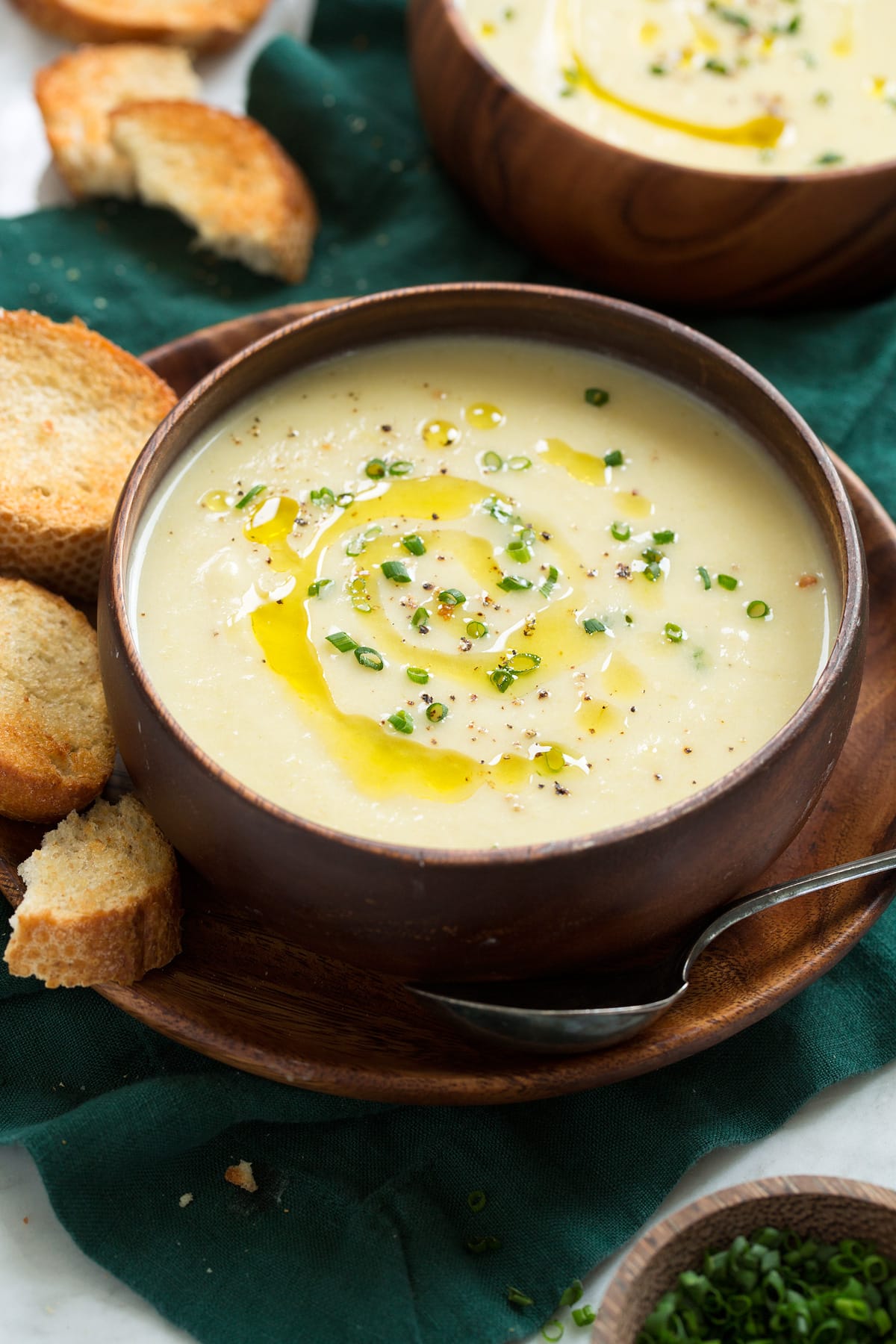 _*Potato Leek Soup*_ /It's a smooth and creamy pureed soup made with a handful of basic ingredients, but the two main highlights of the soup are the fresh leeks and russet potatoes. It's a perfectly sip-able, deliciously tasty, and completely cozy and comforting soup!/   #BayLeaves #Butter #ChickenBroth #Chives #HeavyCream #Leeks #Potatoes #SourCream #Thyme #WhiteWine  Servings: 5 Ready in: 1 hour Prep: 20 minutes Cook: 40 minutes  Ingredients:  2 lbs leeks (about 3 large) 2 Tbsp butter Salt and freshly ground black pepper 1.5 tsp minced garlic (1 large clove) 2/3 cup dry white wine, such as Sauvignon Blanc 6 cups low-sodium chicken broth 1 3/4 lbs. Russet Potatoes, peeled and chopped into chunks about 1-inch thick 1 large thyme sprig 2 bay leaves (fresh or dried) 1/3 cup sour cream or creme fraiche 1/3 cup heavy cream Optional toppings/sides 2 Tbsp minced chives Extra virgin olive oil Toasted baguette slices  Instructions: *1.* Cut the leeks between the white and light green portion and the dark green portion. Slice in half through the length of every portion (creating 6 portions).  *2.* Rinse to remove dirt and debris, shake away excess water. Layer together the darker green portions into 2 snug portions then wrap and tie with kitchen twine (can refer to photos).  *3.* Cut remaining white and light green portion into 1/4-inch slices (you should have about 6 cups).  *4.* Melt butter in a large pot over medium-low heat. Add chopped leeks, season lightly with salt and saute until starting to soften, about 6 to 8 minutes. Add garlic and saute 2 more minutes.  *5.* Pour in white wine and chicken broth, add tied greens (upper leaves) of the leeks, russet potatoes, thyme, bay leaves and season with salt to taste. Press down with a wooden spoon to submerge potatoes and leeks as much as possible.  *6.* Bring to a simmer over medium-high heat. Cover then reduce heat to medium-low and simmer until potatoes are very tender, about 17 to 20 minutes.  *7.* Remove soup from heat. Remove leek greens (leaves) using tongs then press agains side of pan with a wooden spoon to extract juices, discard. Remove thyme sprig and bay leaves, discard.  *8.* Process with an immersion blender until smooth (be mindful not to scratch pot).  *9.* Add sour cream and heavy cream and whisk until smooth. Can rewarm over low heat if needed (don't simmer or the sour cream can curdle).  *10.* Garnish servings with chives, olive oil if desired, and a little black pepper.   Notes: Olive oil and baguette not included in nutrition estimate. For the toasted baguette slices I like to brush lightly with olive oil then rub with a halved garlic clove. From there toast in a countertop toaster oven or on a baking sheet set underneath the broiler of an oven. Recipe makes about 8 cups.  https://www.cookingclassy.com/potato-leek-soup/
