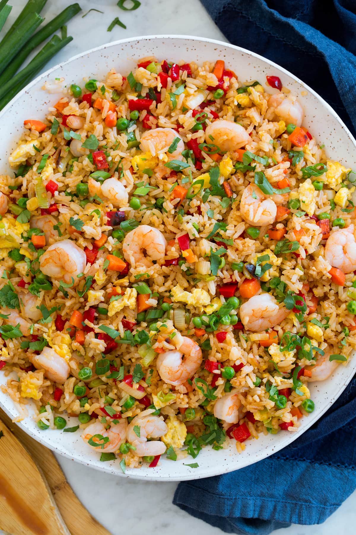 _*Shrimp Fried Rice*_ /This Chinese take-out favorite is made with tender jasmine rice, plenty of fresh vegetables, and high in protein shrimp and eggs. It's an umami rich dish with plenty of crave-able flavor./   #BellPeppers #Carrots #Cilantro #Eggs #Garlic #Ginger #GreenOnions #OysterSauce #Peas #Rice #SesameOil #ShaoxingWine #Shrimp #SoySauce  Servings: 4 Ready in: 40 minutes Prep: 25 minutes Cook: 15 minutes  Ingredients:  1 1/2 Tbsp soy sauce 1 Tbsp shaoxing wine 1 Tbsp oyster sauce 2 tsp sriracha 2 Tbsp light olive oil or vegetable oil 1 lb. small or medium shrimp, peeled and deveined Few pinches salt 1 cup diced carrot (1 extra large) 1 cup diced red bell pepper (1 small) 3/4 cup green onions, white and light green portion, sliced, plus 3 Tbsp green portion for serving 1 Tbsp minced garlic 1 Tbsp peeled and minced ginger 1 Tbsp sesame oil 4 cups leftover cooked jasmine rice* 3 large eggs, blended together in a bowl 1 cup frozen peas (preferably petite) 3 Tbsp chopped cilantro (optional)  Instructions: *1.* In a small mixing bowl whisk together soy sauce, shaoxing wine, oyster sauce, and sriracha. Set aside.  *2.* Preheat skillet with 1 Tbsp olive oil in skillet over medium-high heat.  *3.* Add shrimp and a few pinches of salt and cook 1 minute, turn and cook until opaque and barely cooked through, about 1 minute longer. Transfer to a plate.  *4.* Return skillet to medium-high heat. Add remaining 1 Tbsp olive oil. Add carrots and saute 2 minutes.  *5.* Add bell pepper and white/light portion of green onions. Saute 2 minutes.  *6.* Toss in garlic and ginger and saute 30 seconds longer.  *7.* Scoot mixture to the far side. Drizzle in sesame oil to empty side. Add rice then spread even. Let cook tossing only occasionally about 3 minutes.  *8.* Add the sauce mixture and peas and cook 1 minute longer.  *9.* Scoot mixture to one side of the pan, then add eggs and few pinches of salt and scramble until barely cooked through then break up into small pieces using the bottom of a wooden spatula.  *10.* Return shrimp, add green onion greens and cilantro and toss. Serve warm.   Notes: *I recommend using lightly salted rice. This is about 1 1/4 cups jasmine rice cooked with 2 cups water and 1/4 tsp salt. Recipe makes about 9 cups.    https://www.cookingclassy.com/shrimp-fried-rice/