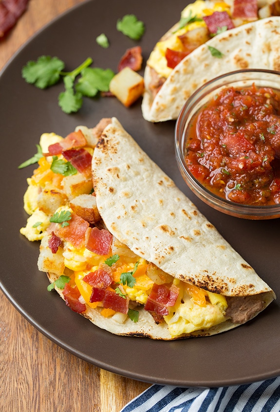 _*Breakfast Tacos*_ /Homemade tortillas are topped with seasoned chorizo or flavorful bacon, then layered with eggs and fresh sauteed peppers, cheese, and vibrant pico de gallo. Easily one of the tastiest breakfasts!/   #Avocado #Bacon #CheddarCheese #Chorizo #Eggs #PoblanoPepper #Tortillas  Servings: 8 tacos Ready in: 55 minutes Prep: 40 minutes Cook: 15 minutes  Ingredients:  16 oz. chorizo (such as Johnsonville) or 12 oz bacon 8 homemade flour tortillas, recipe here, warmed 8 large eggs, whisked in a bowl 1 poblano pepper, seeded and chopped (1 cup) 1 cup shredded cheddar cheese or monterey jack cheese 1 medium avocado, diced 1 cup pico de gallo, recipe here Mexican hot sauce, such as Tapatio or Cholula  Instructions: *1.* Bacon option: Line a rimmed 18 by 13-inch baking sheet with aluminum foil. Place bacon strips side by side on baking sheet in a single layer.  *2.* Place in oven. Set oven to 400 degrees. Bake until bacon is crisp, about 20 to 25 minutes (cook time will vary based on thickness so keep an eye on it even a little early).  *3.* Using tongs transfer bacon strips to a paper towel lined plate to drain, then chop. Reserve 1 Tbsp rendered bacon fat for skillet.  *4.* Chorizo option: Heat a 12-inch non-stick skillet over medium-high heat. Crumble chorizo into small chunks into pan.  *5.* Cook and crumble chorizo until cooked through. Transfer chorizo to a paper towel lined plate to drain while reserving 1 Tbsp rendered fat in pan. Cover chorizo with foil to keep warm.  *6.* Keep 1 Tbsp chorizo fat in pan or add 1 Tbsp rendered bacon fat if going with the bacon option and heat pan over medium heat.  *7.* To cook pepper and eggs: Add poblano and saute until tender, about 4 minutes, scoot peppers to one far side. Reduce burner temperature to low heat.  *8.* Pour whisked eggs into pan on empty side, season lightly with salt and pepper. Cook, scraping along bottom of pan constantly until eggs are just set (it's fine if peppers blend into eggs).  *9.* To assemble breakfast tacos: On serving plates layer warmed tortilla, chorizo or bacon, eggs with peppers, cheese, avocado, pico de gallo and hot sauce. Serve right away.   Notes: Nutrition estimate based on 1 taco using homemade tortillas, and going with the chorizo option.  https://www.cookingclassy.com/breakfast-tacos/