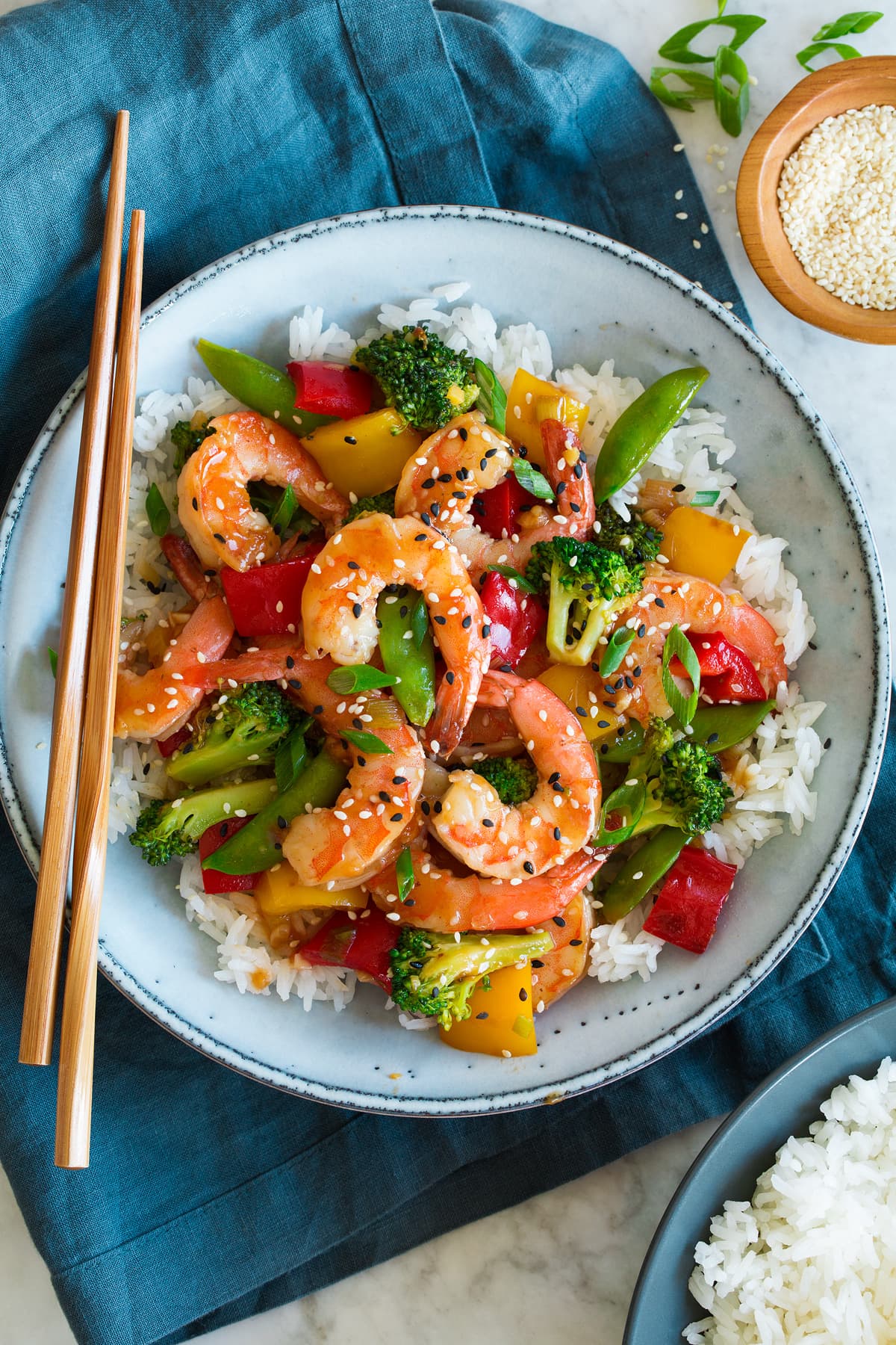_*Shrimp Stir Fry*_ /Made with protein rich shrimp, an abundance of fresh tender-crisp vegetables, and a flavorful savory sauce. It's a weeknight dinner staple!/   #BellPepper #Broccoli #ChickenBroth #Garlic #Ginger #Honey #SesameOil #ShaoxingWine #Shrimp #SnowPeas #SoySauce  Servings: 4 Ready in: 30 minutes Prep: 20 minutes Cook: 10 minutes  Ingredients:  Stir Fry Sauce 1/2 cup low-sodium chicken broth 2 Tbsp soy sauce* 2 Tbsp Shaoxing wine 1 Tbsp honey 2 tsp rice vinegar 1 tsp sriracha 1 tsp sesame oil 1 Tbsp cornstarch Stir Fry 1 lb. large shrimp, peeled and deveined 1 pinch salt 3 Tbsp vegetable oil or olive oil 1 1/2 cups (slightly packed) small broccoli florets 1 1/2 cups (5 oz) snow peas 1 1/2 cups chopped bell pepper (red and/or yellow) 1/2 cup chopped green onions, just light and white green portion 1 Tbsp minced garlic 2 tsp minced ginger 1 tsp sesame seeds, optional  Instructions: *1.* In a medium mixing bowl whisk together chicken broth, soy sauce, Shaoxing wine, honey, rice vinegar, sriracha, sesame oil and cornstarch until well blended.  *2.* Heat 1 Tbsp oil in a 12-inch non-stick skillet over medium-high heat.  *3.* Dab shrimp dry, add to skillet and quickly spread into a single even layer (no overlapping). Season with a pinch of salt.  *4.* Let cook about 1 to 1 1/2 minutes until pink on bottom side. Quickly turn shrimp then let cook until pink on opposite side and opaque throughout, about 1 to 1 1/2 minutes longer.  *5.* Transfer shrimp to a plate.  *6.* Heat remaining 2 Tbsp oil in skillet. Add broccoli saute 1 minute. Add snow peas, bell pepper and green onions and saute 3 - 4 minutes until veggies are tender crisp.  *7.* Add garlic and ginger and saute 30 seconds longer.  *8.* Whisk sauce once more then pour into skillet. Let cook until thickened, stirring constantly, about 1 minute.  *9.* Return shrimp to skillet and toss to coat with sauce.  *10.* Sprinkle with sesame seeds if using and optionally you can garnish with a some sliced green onions for garnish. Serve right away over rice if desired.   Notes: *If you need to reduce salt in the recipe use unsalted chicken broth, unsalted Shaoxing wine, and low-sodium soy sauce.  https://www.cookingclassy.com/shrimp-stir-fry/