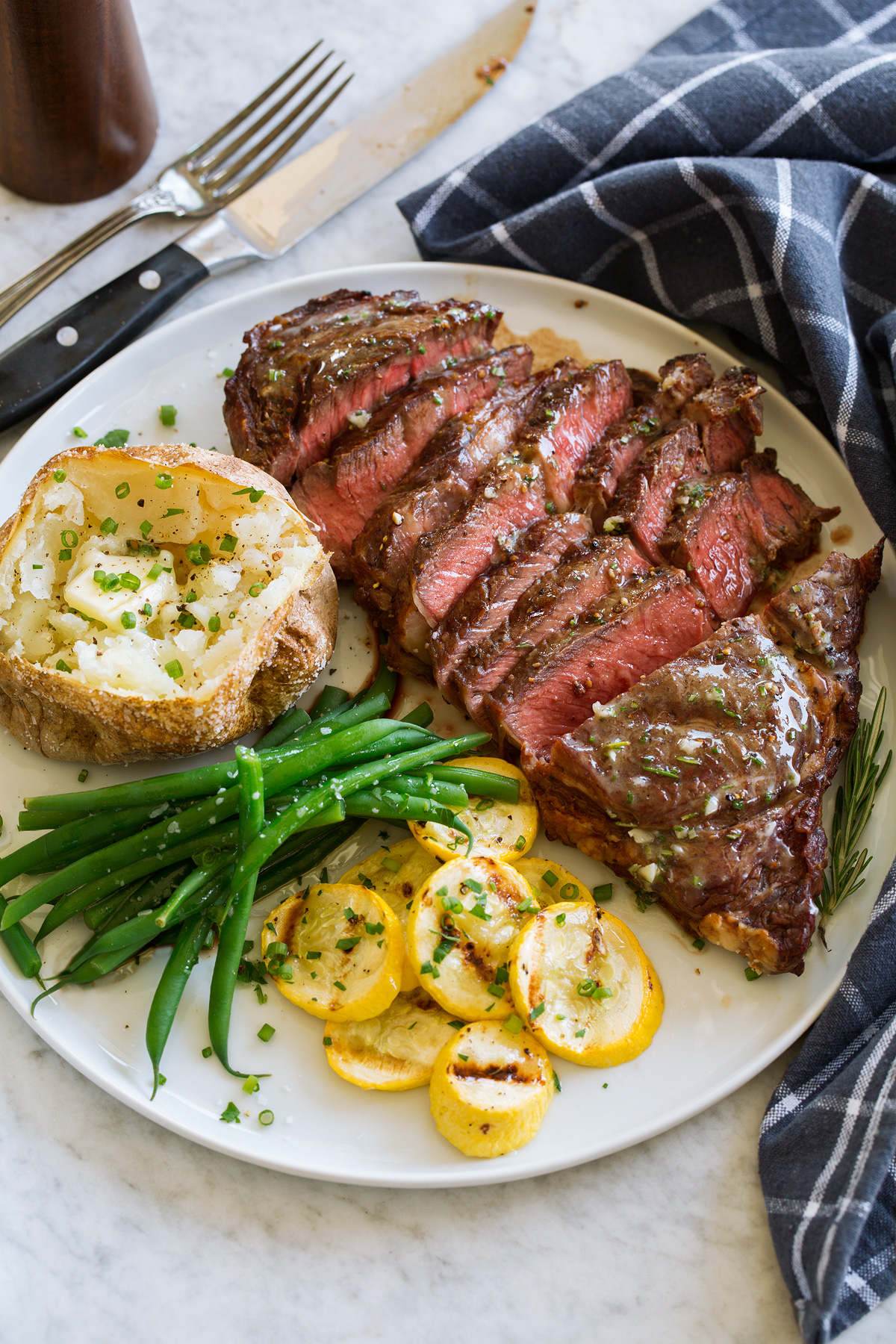 _*Grilled Steak*_ /Perfectly Grilled Steak – it’s the ultimate meat to serve at a backyard cookout and there’s hardly anything to it. With this easy method you’ll end with beautifully sear marked steak, a juicy and tender interior and a glossy buttery finish./   #Butter #Garlic #Rosemary #Salt #Steak  Servings: 4 (1/2 steak per person) Ingredients:  2 (1 lb. each) ribeye steaks,* 1 1/4 to 1 1/2-inches thick (I use boneless) 1 1/2 tsp kosher salt, or as desired 1 tsp freshly ground black pepper 4 Tbsp butter 2 tsp minced fresh rosemary** 3/4 tsp minced fresh garlic  Instructions: *1.* Place steaks on a plate. Sprinkle each side evenly with a fair amount of kosher salt.  *2.* Let steak rest at room temperature 45 minutes to 60 minutes. *** *3.* Meanwhile in a small mixing bowl stir together butter, rosemary and garlic. Set aside.  *4.* Heat a grill over moderately high heat, to about 450 to 500 degrees.  *5.* Sprinkle each side of both steaks with pepper.  *6.* Grill steaks about 3 1/2 to 7 minutes per side to desired doneness. **** Rare steaks will be near lesser time while more well done will be near greater time. Use an instant read food thermometer to test for doneness in center of thickest portion of steak.  *7.* Let steaks rest off heat 5 minutes. Brushed with the garlic herb butter, slice and serve.   Notes: *Ribeye, New York strip steak, filet mignon (tenderloin), or T-bone work well here. **1 1/2 tsp fresh thyme or 1 Tbsp minced fresh parsley will work in place or rosemary. ***Steak can be salted up to 48 hours in advance (if it's not about to spoil). If doing so just salt each steak and keep on a wire rack in the fridge uncovered. ****STEAK DONENESS TARGET TEMPERATURES Note that the FDA recommends an internal temperature of 145 degrees with a 3 minute resting period for food safety.  Rare: 115 - 120 degrees, serve steak at 125 degrees Medium rare: 120 - 125 degrees, serve at 130 degrees Medium: 130 - 135 degrees, serve at 140 degrees Medium well: 140 - 145 degrees, serve at 150 degrees Well: 150 - 155 degrees, serve at 160 degrees    https://www.cookingclassy.com/grilled-steak/