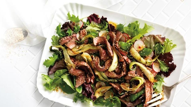 _Grilled Beef and Bok Choy Salad_ /Grilling bok choy adds to its flavour, while keeping its crunchy texture. This salad is ideal for a light summer meal!/  *Grilling Time:* 15 minutes *Preparation Time:* 25 minutes *Cooking Time:* 10 minutes *Serves:* 4  _Ingredients_  1/4 cup (50 mL) *each* vegetable oil, rice vinegar and soy sauce  2 tbsp (25 mL) sesame oil  2 tbsp (25 mL) Honey  3 cloves Garlic, minced  1-1/2 tsp (7 mL) Asian chili sauce  2 Beef Striploin Steaks (8 oz/250 g *each*)  4 Baby Bok Choy (about 12 oz/375 g)  2 cups (500 mL) Snow Peas, trimmed  4 Radishes, halved and thinly sliced  6 cups (1.5 L) Mixed Greens  1 tbsp (15 mL) toasted sesame seeds  _Instructions_ In measuring cup, combine vegetable oil, vinegar, soy sauce, sesame oil, honey, garlic and chili sauce. Pour 1/4 cup (50 mL) over steaks, turning to coat; cover and set aside in refrigerator to marinate.  Meanwhile, trim ends from bok choy; cut in half lengthwise. In large bowl, toss bok choy with 1/4 cup (50 mL) dressing to coat. Grill over medium heat, turning once, for about 8 minutes. Return to bowl and cover with plastic wrap; let stand until tender-crisp, about 10 minutes.  Grill steaks over medium-high for 3 to 4 minutes per side for medium-rare, or until desired doneness. Let stand covered for 5 minutes before slicing.  Meanwhile, in large pot of boiling salted water blanch snow peas for 1 to 2 minutes or until tender-crisp. Drain and plunge into bowl of ice water; drain and pat dry.  Drain any liquid from bok choy; cut each half in half again lengthwise and return to bowl. Add snow peas and radishes; drizzle a little of remaining dressing, tossing to coat. Place greens on large platter. Top with bok choy mixture and sliced beef. Sprinkle with sesame seeds. Serve with remaining dressing.  *Tip:* Use Chili-Garlic sauce instead for a different flavour combination.  _Nutritional information_  *Protein:* 33 grams  *Fat:* 16 grams  *Carbohydrate:* 18 grams  *Fibre:* 4 grams  *Calories:* 350  *Sodium:* 825 mg
