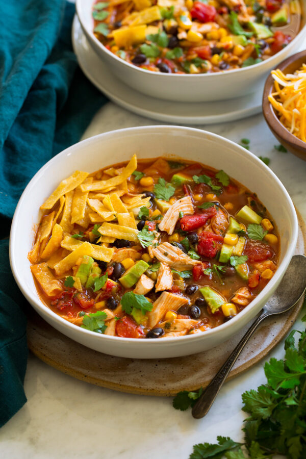 _*Chicken Tortilla Soup*_ /Quick and easy Chicken Tortilla Soup! Bursting with flavor and always sure to satisfy! Made with tender rotisserie chicken, hearty black beans, nutritious vegetables, and a bright and savory, well seasoned broth. A recipe most definitely worthy for a space in the recipe box!/ Makes about 10 3/4 cups #BlackBeans #Chicken #ChickenBroth #ChiliPowder #Cilantro #Corn #Cumin #Garlic #Jalapeno #Lime #Onion #TomatoSauce #Tomatoes #TortillaChips Servings: 7 Ready in: 35 minutes Prep: 15 minutes Cook: 20 minutes Ingredients: 1 1/2 Tbsp olive oil 1 1/4 cups finely chopped yellow onion (1 small) 1 medium jalapeno*, seeded and minced (1/4 cup) 1 1/2 Tbsp minced garlic (4 cloves) 1 Tbsp chili powder 2 tsp ground cumin 1 (32 oz) carton Swanson Chicken Broth 1 (15 oz can) tomato sauce 1 (14.5 oz) can fire roasted diced tomatoes 1 1/2 cups frozen corn 3 cups shredded rotisserie chicken (I use breast and thigh meat) 1 (14.5 oz) can black beans, drained and rinsed 1/2 cup chopped cilantro 1 Tbsp fresh lime juice Salt and freshly ground black pepper Toppings 4 oz. corn tortilla strips**, or tortilla chips slightly crushed 1 cup shredded Mexican cheese or Monterey jack cheese diced avocado (optional) sour cream (optional) Instructions: *1.* Heat olive oil in a large pot over medium-high heat. Add onion and jalapeno and saute until nearly soft, about 6 - 7 minutes. *2.* Add garlic, chili powder and cumin and saute 1 minute. *3.* Pour in chicken broth, tomato sauce, diced tomatoes and corn. Bring mixture to a simmer, then reduce heat to medium, cover and let simmer 5 - 10 minutes. *4.* Stir in chicken, black beans, cilantro and lime. Season soup with salt and pepper as needed. *5.* Ladle into bowls top with tortilla chips, cheese and optional avocado or sour cream. Notes: *If you don't like heat then 1/2 cup chopped bell pepper can be substituted. If you love heat then keep the seeds and even add an extra jalapeno. **To make your own tortilla strips you can cut 6 corn tortillas in half and cut into strips. Then pour 1/2-inch of vegetable oil into a pot or saute pan and heat to 350 degrees. Fry half of the strips at a time until crisp, about 2 minutes, use a spicer to collect and strain then transfer to paper towels to drain and season with salt right away. Nutrition estimate based on about 1.5 cups soup per serving. Does not include avocado or sour cream.
