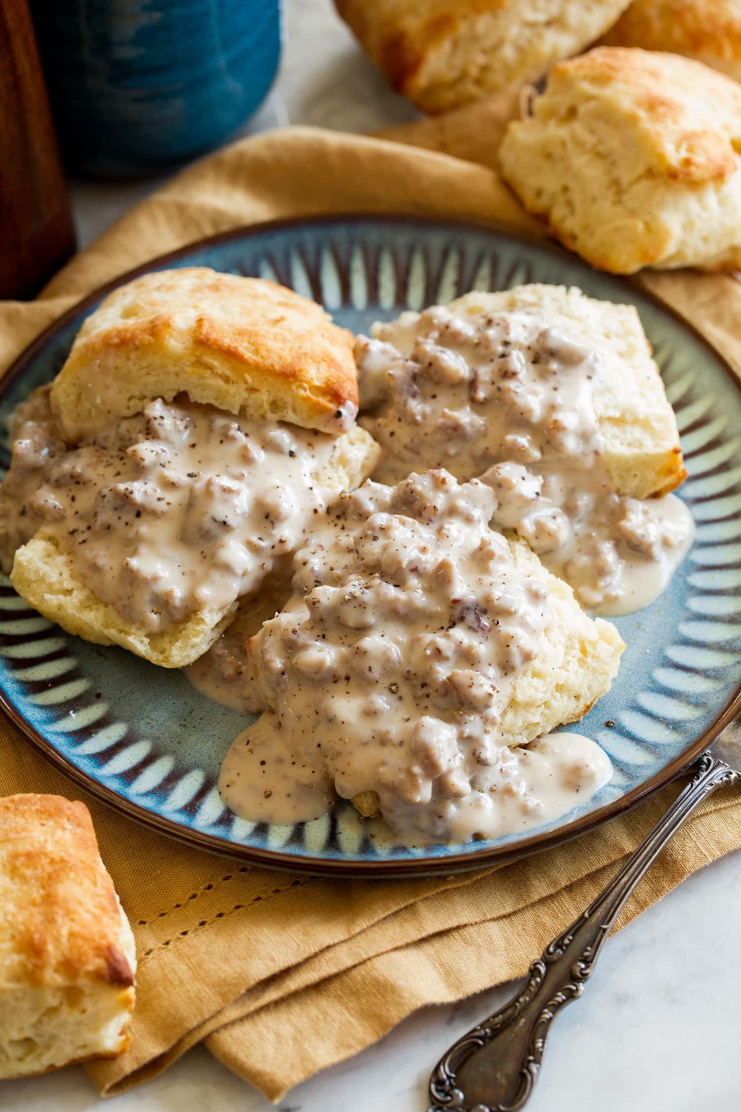 _*Biscuits and Sausage Gravy*_ /The ultimate breakfast comfort food made with buttery, flaky homemade biscuits that are topped with a rich and creamy, simple sausage gravy./   #Butter #Buttermilk #Flour #Milk #Sausage #Sugar  Servings: 8 Ready in: 20 minutes Prep: 5 minutes Cook: 15 minutes  Ingredients:  Biscuits 2 cups (283g) all-purpose flour (scoop and level to measure) 1 Tbsp aluminum free baking powder 2 tsp granulated sugar 1/4 tsp baking soda 8 Tbsp (113g) unsalted butter, divided, 7 Tbsp cold, 1 Tbsp melted 1 cup (235ml) buttermilk, cold Gravy 1 lb. pork breakfast sausage 1/3 cup (47g) all purpose flour Salt and pepper, to taste 3 cups (710ml) whole milk 2 Tbsp butter, if needed  Instructions: *1.* Preheat oven to 450 degrees. Line an 18 by 13-inch baking sheet with parchment paper.  *2.* In a large mixing bowl whisk together flour, baking powder, sugar, baking soda and salt for 20 seconds.  *3.* Cut 7 Tbsp cold butter into small cubes. Add to flour mixture and cut butter into mixture with a pastry cutter until there are small clumps of butter about the size of peas, make a well in the center of mixture.  *4.* Pour buttermilk into well then fold mixture with a rubber spatula until it comes together. Gently turn and press dough to bring together completely, then drop onto a lightly floured surface.  *5.* Gently roll dough out to a large rectangle, about 10 by 9. Fold in half then repeat gently rolling and folding process twice more.  *6.* Gently roll and shape final rectangle to 9 1/2-inches by 4 3/4-inches (nearly 1-inch high).  *7.* Cut dough into 8 squares (dust knife with flour as needed), when cutting cut straight down in one cut rather then moving side to side downward as this will seal edges.  *8.* Transfer to baking sheet spacing apart. Bake in preheated oven 10 - 13 minutes until golden brown and cooked through. Brush with 1 Tbsp melted butter after baking.  *9.* Set a 12-inch oiled cast iron skillet over medium-high heat. Break sausage into chunks and add to pan. Let sear on bottom for a couple of minutes until browned then start to break up and toss sausage.  *10.* Let cook until no longer pink, tossing occasionally. Melt butter in with sausage near the end.  *11.* Reduce heat to medium. Sprinkle in flour and season with pepper to taste (I use a fair amount, about 1 tsp), then cook stirring constantly 1 - 2 minutes.  *12.* While stirring pour in milk, season with salt to taste. Cook stirring frequently until mixture simmers and thickens. If needed pour in more milk to thin to reach desired consistency. Serve warm over halved biscuits.   Notes: If there isn't enough rendered fat from the sausage butter is added to make a proper roux. If the flour doesn't have enough fat to make a paste it will be dry and the gravy will taste floury.  Nutrition estimate includes adding 1 Tbsp butter, but does not include biscuits.