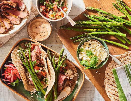 _*Grilled Asparagus and Steak Tacos*_ /Change-up family favourite tacos to include seasonal asparagus. This versatile recipe works well with Ontario rainbow trout or chicken. The pickled radishes are also an excellent addition to salads./   #Dinner #MainDishes #CalendarRecipe  Cooking Time: 3 minutes Grilling Time: 5 minutes Preparation Time: 20 minutes  Ingredients:  Pickled Radishes: 1/2 cup (125 mL) each white vinegar and water 1/2 tsp (2 mL) each salt and granulated sugar 3 Ontario Radishes, julienned Pico de Gallo: 1 Ontario Greenhouse Tomato, finely diced 3 tbsp (45 mL) chopped fresh Ontario Coriander (Cilantro) 2 tbsp (25 mL) finely chopped Ontario Onion 2 tbsp (25 mL) fresh lime juice 1/4 tsp (1 mL) each salt and crushed red pepper flakes Tacos: 1/2 cup (125 mL) Ontario Sour Cream 1 tbsp (15 mL) chipotle hot sauce 1 lb (500 g) Ontario Asparagus, trimmed 1 tsp (5 mL) vegetable oil Pinch each salt and pepper 8 6-inch (15 cm) flour tortillas 1/2 cup (125 mL) crumbled Ontario Feta Cheese 250 g Ontario Grilling Beef Steak, grilled and sliced    Instructions: *1.* Pickled Radishes: In small saucepan, over medium-high heat, bring to boil vinegar, water, salt and sugar. Add radishes. Remove from heat; let stand 5 minutes. Drain and refrigerate.  *2.* Pico de Gallo: In medium bowl, stir together tomato, coriander, onion, lime juice, salt and red pepper flakes. Set aside.   *3.* Tacos: In small bowl, stir together sour cream and hot sauce.  *4.* Brush asparagus with oil, season with salt and pepper. Grill over medium-high heat, until lightly charred, about 5 minutes. During last minute, add tortillas to grill. Flip once; grill until warm.  *5.* Spread each tortilla with sour cream mixture; spoon on Pico de Gallo. Sprinkle with feta; top with steak, asparagus and radishes.  