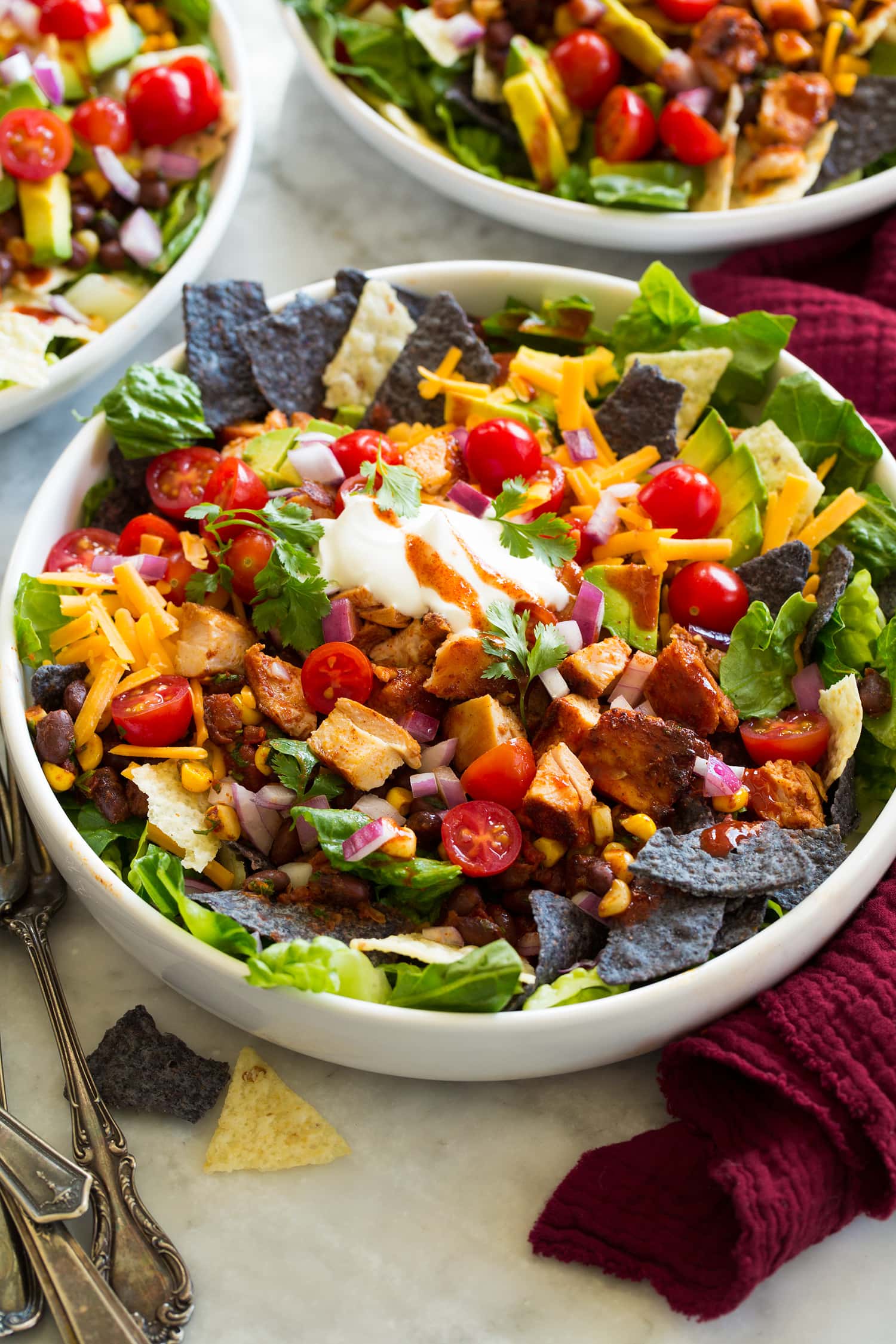 _*Chicken Taco Salad*_ /Loaded Chicken Taco Salad – Made with protein rich chicken and black beans, fresh veggies, tortilla chips, and all the best toppings. It’s brimming with goodness and completely delicious!/   #AppetizersSalads #MainDish #MexicanAndSouthwestern #Avocados #BlackBeans #CheddarCheese #ChickenThighs #ChiliPowder #Cilantro #Corn #Cumin #Garlic #Lettuce #Limes #OliveOil #RedOnions #Salsa #SourCream #Tomatoes #TortillaChips  Prep: 25 minutes. Cook: 20 minutes. Ready in: 45 minutes.  Ingredients: 1: 1.5 lbs. boneless skinless chicken thighs, trimmed of excess fat. 2: 3 Tbsp olive oil, divided. 3: 2 Tbsp fresh lime juice. 4: 4 tsp chili powder, divided. 5: 2 tsp ground cumin. 6: 2 tsp minced garlic. 7: 1 1/2 tsp salt, then to taste. 8: 1 tsp black pepper. 9: 1 can black beans, drained and rinsed. 10: 1 ear fresh corn, husked and kernels cut from cobs, or 1 cup frozen corn. 11: 3/4 cup fresh salsa, homemade or store-bought. 12: 1/3 cup chopped cilantro. 13: 6 cups chopped romaine lettuce. 14: 4 oz. corn tortilla chips (white, yellow or blue). 15: 1 cup shredded cheddar cheese or Monterey jack cheese. 16: 1 1/2 cups grape tomates, halved or 2 roma tomatoes, chopped. 17: 1 avocado, chopped. 18: 1/2 cup chopped red onion. 19: 1/2 cup sour cream. 20: Mexican hot sauce, to taste.  Instructions: 1: In a large mixing bowl whisk together 2 Tbsp lime juice, 2 Tbsp olive oil, 3 tsp chili powder, the cumin, garlic, 1 1/2 tsp salt (or to taste) and pepper. 2: Add chicken to the mixture and toss well to evenly coat. Cover and refrigerate 1 hour and up to 24 hours. 3: Preheat a cast iron skillet over medium-high heat. Drizzle in 1/2 Tbsp olive oil. Add chicken in a single layer leaving space between the thighs. 4: Cook until golden brown on bottom, about 6 minutes. Turn chicken and continue to cook until center registers 165 degrees on each pieces, about 6 minutes longer. Transfer to a plate and let rest 5 minutes before cutting into small pieces. 5: Meanwhile clean skillet of any burnt bits then return to medium-high heat. Add remaining 1/2 Tbsp olive oil and saute corn for 2 minutes. Add black beans, salsa and remaining 1 tsp chili powder and season with salt to taste. Cook about 2 minutes to warm through then remove from heat and toss in cilantro. 6: To plate taco salad to four individual plates or pasta style bowls evenly divide lettuce, chips, bean filling mixture, chicken, cheese, tomatoes, avocado, red onion, sour cream, and serve with hot sauce. 