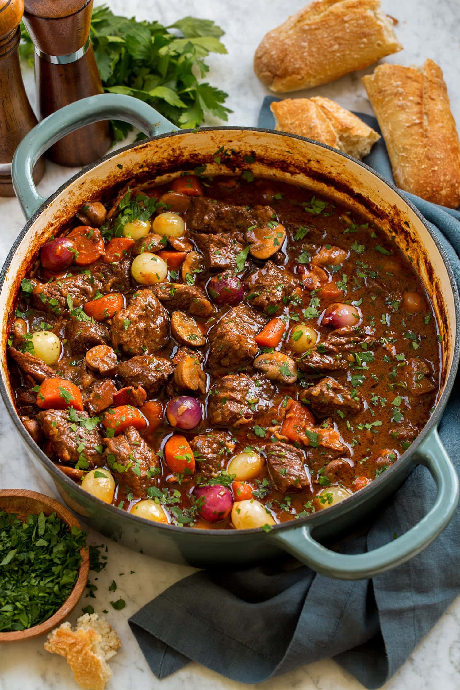 _*Beef Bourguignon*_ /This ultra cozy Beef Bourguignon recipe is one of the most hearty and richly flavorful dishes you’ll ever make! It includes super tender beef portions simmered in a savory red wine sauce, and an abundance of fresh vegetables to round it out./   #BeefBourguignonBeefBourguignonRecipe #BeefAndPork #MainDish #Bacon #BayLeaf #Beef #BeefBroth #Carrots #Flour #Garlic #Mushrooms #Onions #Parsley #RedWine #Rosemary #SoySauce #Thyme #TomatoPaste  Prep: 45 minutes. Cook: 3 hours. Ready in: 3 hours 45 minutes.  INGREDIENTS: 1: 8 oz. bacon, cut into 1-inch pieces. 2: 3 lbs. chuck roast*, cut into 1 1/2 to 2-inch chunks. 3: Salt and black pepper. 4: 1 small yellow onion, chopped (1 cup). 5: 3 garlic cloves, minced (1 Tbsp). 6: 2 Tbsp tomato paste. 7: 3 Tbsp all purpose flour. 8: 2 1/2 cups dry red wine, such as Pinot Nior or Cortes du Rhone. 9: 2 cups low-sodium beef broth or chicken broth, store bought or homemade, then more as needed. 10: 1 Tbsp soy sauce. 11: 2 tsp chopped fresh thyme. 12: 2 tsp chopped fresh rosemary. 13: 1 bay leaf. 14: 4 medium carrots, cut into 1-inch chunks. 15: 8 oz. cremini mushrooms or button mushrooms, halved if small, sliced thick if larger. 16: 8 oz. pearl onions, peeled**. 17: 2 Tbsp olive oil. 18: 2 Tbsp chopped fresh parsley.  INSTRUCTIONS:  1: Preheat oven to 350 degrees. 2: Spray a an oven safe pot or braiser with non-stick cooking spray, add bacon and cook over medium-low heat. Cook, stirring occasionally, until bacon is golden brown and just crisp. Transfer bacon to a paper towel lined plate to drain and reserve fat in pot. Keep bacon in fridge. 3: Working with half the chuck roast, dab it dry with paper towels and season both sides with salt and pepper (I actually go somewhat light when seasoning then just add more to the dish later on if needed). 4: Return pot to medium heat. Add half the chuck roast pieces and brown on both sides, about 3 minutes per side. Transfer to a plate and repeat with remaining half. 5: In now empty pot return to medium heat, add onion and saute 3 minutes. Add garlic and tomato paste and saute 1 minute. Add flour and saute 1 minute. 6: Pour in red wine while scraping up browned bits from the bottom of the pot. Pour in broth and soy sauce. Add thyme, rosemary and bay leaf. 7: Return beef to pot, add carrots. Bring mixture to a simmer. Cover with lid then transfer to oven. Bake until chuck roast pieces are tender, stirring once halfway through, for about 2 hours. 8: During the last 15 minutes of cooking, heat olive oil in a skillet over medium heat. Add mushrooms and pearl onions and saute for about 12 to 15 minutes until golden brown. 9: Add mushroom and onion mixture, plus the bacon to the beef stew mixture and stir. Season with salt and pepper to taste as needed. 10: Garnish servings with fresh parsley. Serve with mashed potatoes or fresh bread if desired. Notes: *Look for a chuck roast marbled with thin weaves of fat throughout the beef, if possible avoid those with many large chunks of fat as you'll just have to cut off and discard that fat and you won't end up with as much usable beef in the recipe. **To peel fresh pearl onions drop in a pot of boiling water for 1 minute. Drain then cool. Cut root ends and squeeze onion downward to root tip to remove, then cut tops. Frozen pearl onions may be used here as well. Add them after about 10 minutes of browning the mushrooms since they are already par-cooked.  