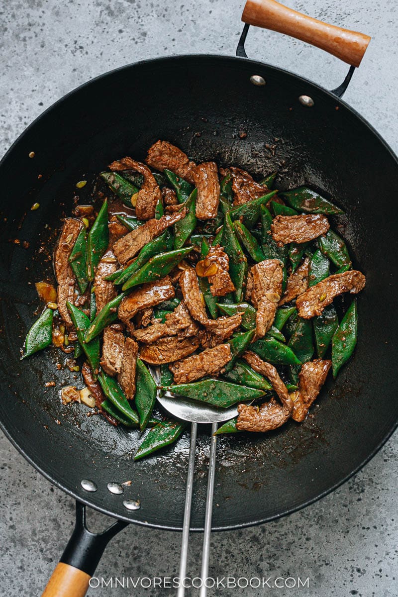_*Beef and Flat Bean Stir Fry*_

/Beef and flat bean stir fry is a quick main dish featuring juicy tender beef and thick romano beans brought together with a fragrant brown sauce./

[To make this dish gluten-free, use tamari to replace soy sauce, and use dry sherry instead of Shaoxing wine.]

Prep Time: 15 minutes
Cook Time: 10 minutes
Total Time: 25 minutes
Servings: 2 to 3 servings

_Ingredients_ 
Meat and Marinade: 
300 g (10 oz) boneless flank steak , skirt steak, or other cut (*see footnote 1)
1 teaspoon soy sauce
1/4 teaspoon salt
1 teaspoon peanut oil (or vegetable oil)
1 teaspoon cornstarch

Sauce:
2 tablespoons chicken broth (or beef broth)
1 tablespoon Shaoxing wine (or dry sherry)
1 tablespoon soy sauce
1/2 teaspoon dark soy sauce (*footnote 2)
1/4 teaspoon sugar
1 teaspoon cornstarch

Stir-fry:
300 g (10 oz) flat beans , cut to 1” (1.5 cm) pieces
1 tablespoon peanut oil (or vegetable oil)
1 clove garlic , sliced
1/2 thumb ginger , sliced

Instructions:
1: Slice the beef against the grain into 0.5 cm (1/4 inch) thick slices or 1-cm (1/2 inch) sticks. Transfer to a small bowl. Add soy sauce and salt (*Footnote 1). Gently mix well by hand until all the slices are coated. Add the peanut oil and cornstarch. Mix again to combine evenly. Marinate for 15 minutes while preparing the other ingredients.

2: Combine all the ingredients for the sauce in a medium-sized bowl. Mix well.

3: Bring a medium pot of water to a boil. Add the flat beans and boil for 5 minutes, or until the beans turn tender. Drain and run the beans with tap water for a few seconds, to stop cooking. Then drain again thoroughly and set aside.

4: Heat oil a large skillet or a wok until hot. Swirl to coat the bottom. Spread the steak in a single layer. Allow to cook without touching for 30 seconds, or until the bottom side is browned. Flip to cook the other side for a few seconds. Stir and cook until the surface is lightly charred and the inside is still a bit pink. Transfer to a plate.

5: The pan should still have some oil left. If not, add 2 teaspoons of oil. Add the garlic and ginger. Stir a few times to release the flavor and fragrance.

6: Add the flat beans to the pan. Stir and cook for 1 minute. Add the beef back to the pan.

7: Stir the sauce again to dissolve the cornstarch completely and pour it into the skillet. Cook and stir until the sauce thickens. Transfer everything to a plate immediately. Serve hot as a main dish.

Notes:
1: If you need to use a cheaper or tougher cut of beef, for example, chuck, brisket, or round roast, add 1/4 teaspoon of baking soda to the marinade and marinate the beef for 30 minutes before cooking. This method tenderizes the beef and will create a very juicy result.

2: Dark soy sauce will add an appetizing dark color to the sauce with a hint of caramel taste, but you can skip it if you don't have it. If you skip the dark soy sauce, you can add 1/2 teaspoon molasses to enhance the flavor.

