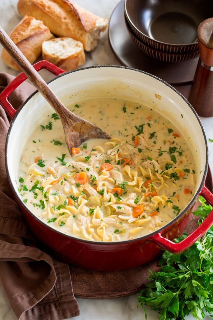 _*Creamy Chicken Noodle Soup*_ /It's a tasty upgrade on classic chicken noodle soup with a creamy base, browned chicken, lots of veggies and tender curly noodles. Such a cozy favorite!/   #BayLeaves #Butter #Carrots #Celery #Chicken #ChickenBroth #Cream #Flour #Milk #OliveOil #Onions #Parsley #Pasta  Servings: 5 (about 10 cups) Ready in: 55 minutes Prep: 30 minutes Cook: 25 minutes  Ingredients:  1 lb. boneless skinless chicken breasts, about 2 large 1 1/2 Tbsp olive oil, divided 1 1/2 cups chopped yellow onion (1 medium) 1 1/2 cups chopped carrots (3 carrots) 1 1/2 cups chopped celery (3 stalks) 1 Tbsp minced garlic, (3 cloves) 4 cups low-sodium chicken broth, can add more to thin near end if desired 1 Tbsp chopped fresh thyme leaves, or 1 tsp dried 2 bay leaves Salt and black pepper 1/3 cup butter 6 Tbsp all-purpose flour 2 1/2 cups whole milk 1/4 cup heavy cream 2 cups dry medium egg noodles 3 Tbsp chopped fresh parsley  Instructions: *1.* Heat 1 Tbsp olive oil in a large pot over medium-high heat. Pound chicken to an even thickness using a meat mallet then dab chicken dry with paper towels and season both sides with salt and pepper.  *2.* Sear chicken in pot until browned on both sides, about 4 minutes per side (it won't be fully cooked through at this point). Transfer to a plate.  *3.* Heat remaining 1/2 Tbsp olive oil in pot. Add onion, carrot and celery and saute 5 minutes, then add garlic and saute 1 minute longer.  *4.* Add chicken broth, thyme, bay leaves and season with salt and pepper to taste. Add chicken breasts and bring soup to a simmer.  *5.* Reduce heat to low, cover with lid and allow soup to cook until chicken has cooked through, about 5 to 10 minutes longer (cook time will vary depending on thickness of chicken breasts).  *6.* Meanwhile in a medium saucepan melt butter over medium heat, add flour and cook, stirring constantly, 2 to 3 minutes until it's a deeper golden. While whisking slowly add in milk and whisk vigorously to smooth lumps.  *7.* Whisk in cream to milk mixture then bring mixture to a simmer, stirring constantly (scrape bottom edges as well).  *8.* Remove cooked chicken from soup and allow to rest for 5 minutes, then shred into small bite size pieces. Meanwhile add noodles to soup, cover and cook until tender, about 6 to 12 minutes (or according to time on package).  *9.* Turn heat off soup. Pour milk mixture into soup mixture and return shredded chicken to soup. Stir in parsley. Let soup cool slightly before serving.   Notes: Making This Soup In Advance? This soup won't freeze well because it contains dairy which tends to split and curdle when frozen but you can prepare this in advance and store it in the fridge. Important tips to remember when making this soup in advance are to not add the noodles until you are serving it. If you add them to the soup prior to serving the noodles will swell up and become mushy.