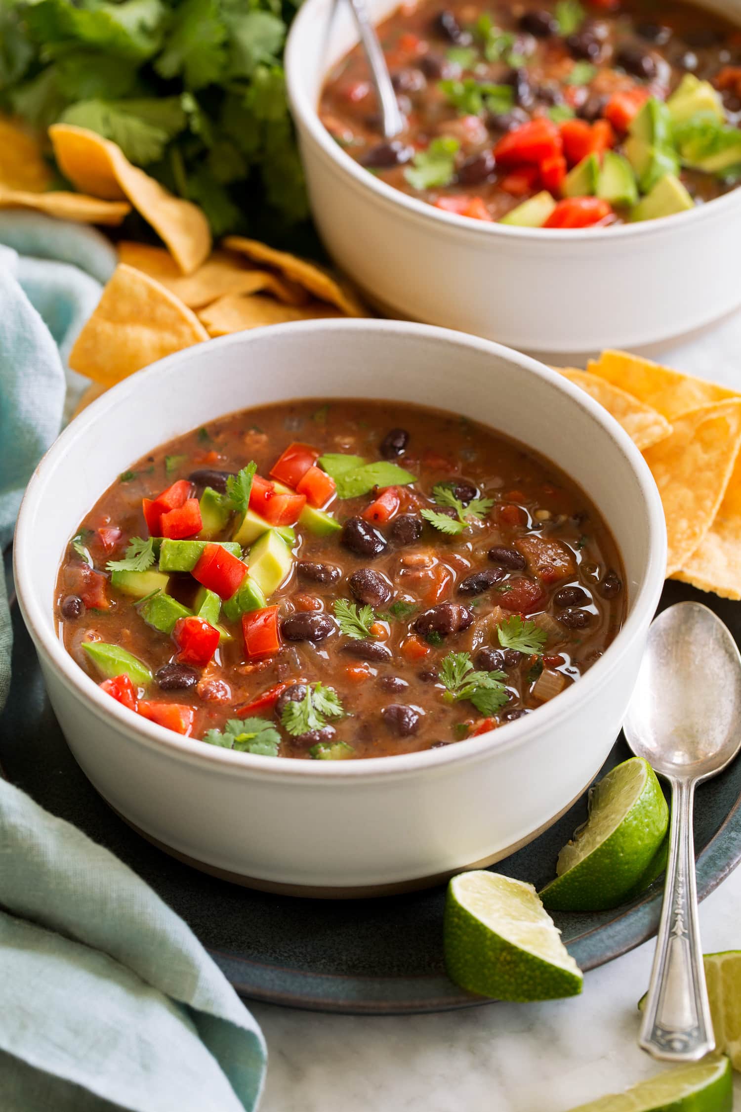 _*Black Bean Soup*_ /A hearty, nutritious, protein rich black bean soup with lots of delicious flavor! Plus it's brimming with toppings for extra layers of goodness and satisfying textures./   #AnchoChiliPowder #Avocados #BlackBeans #ChickenBroth #Cilantro #Garlic #LimeJuice #Onions #PoblanoPepper #SourCream #Tomatoes  Servings: 6 Ready in: 25 minutes Prep: 5 minutes Cook: 20 minutes  Ingredients:  4 (14.5 oz) cans black beans, divided 6 slices (7 oz) bacon, chopped into small pieces 1 large yellow onion, chopped (1 3/4 cups) 1 medium red bell pepper or 1 large poblano pepper, seeded, stemmed and diced small 4 tsp minced garlic (4 cloves) 2 (14.5 oz) cans low-sodium chicken broth, divided 1 (14.5 oz) can fire roasted diced tomatoes 1 tsp chili powder (regular or Ancho) 1 tsp ground cumin Salt and black pepper 1 Tbsp fresh lime juice 1/3 cup chopped cilantro Toppings for serving (optional) Sour cream , cheese (shredded Mexican or cheddar cheese), diced avocado, diced roma tomatoes, chopped cilantro, tortilla chips  Instructions: *1.* Place 1 1/2 cans of drained black beans in a food processor along with 1/2 cup of the chicken broth and pulse until well pureed. Rinse remaining 2 1/2 cans of black beans in a colander. Set all black beans aside.  *2.* Heat a large pot over medium heat. Add bacon and cook until crisp, tossing occasionally. Transfer to a paper towel lined plate leaving rendered bacon fat in pot.  *3.* Add in onions and bell pepper or poblano pepper to pot and saute 3 minutes then add garlic, chili powder and cumin and saute 1 minute longer. Stir in remaining chicken broth (3 cups).  *4.* Pour in remaining chicken broth (3 cups) black beans, black bean puree mixture, fire roasted tomatoes, and season with salt and pepper to taste.  *5.* Bring to a boil then reduce heat to medium-low, cover and simmer 15 minutes, stirring occasionally.  *6.* Stir cooked bacon, lime juice and cilantro and serve warm with desired toppings.