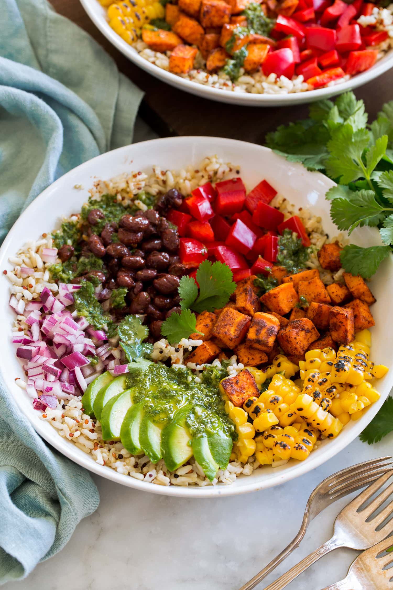 _*Baja Grain Bowls*_ /A healthy rainbow Baja Grain Bowl made with nutritious brown rice and quinoa, vitamin packed veggies including bell pepper, sweet potatoes, corn, avocado and red onion. And it also includes hearty black beans to make it more filling and add more fiber and protein./   #AnchoChiliPowder #Avocados #BellPeppers #BlackBeans #BrownRice #Cilantro #Cumin #Garlic #Limes #OliveOil #Quinoa #RedOnions #SmokedPaprika #SweetPotatoes  Servings: 4 Ready in: 55 minutes Prep: 30 minutes Cook: 25 minutes  Ingredients:  2 cups cooked brown rice 1 cup cooked tri color quinoa (OR another 1 cup cooked brown rice) 20 oz. sweet potatoes, peeled and cut into 1/2-inch cubes (or chicken see notes*) 1 Tbsp olive oil 1 tsp each cumin, smoked paprika, and ancho chili powder Cayenne pepper to taste Salt and black pepper 1 (14.5 oz) can black beans, drained 1 1/4 cups corn (raw or cooked) 1 red bell pepper, chopped or 1 cup chopped tomatoes 1 avocado, sliced 1/2 cup chopped chopped red onion Dressing 1/3 cup olive oil 2 1/2 Tbsp fresh lime juice, plus 1 tsp lime zest 1 medium garlic clove, minced 1 tsp honey or maple syrup 1/2 cup (slightly packed) fresh cilantro  Instructions: *1.* Preheat oven to 400 degress. Spray a rimmed 18 by 13-inch baking sheet with non-stick cooking spray.  *2.* Place sweet potatoes on baking sheet in a mound, drizzle over 1 Tbsp olive oil, add 1/2 tsp of each cumin, smoked paprika and ancho chili powder. Season with salt and pepper to taste, toss potatoes well to evenly coat then spread into an even layer.  *3.* Bake in preheated oven 15 minutes. Toss then return to oven and continue to roast until tender, about 10 minutes longer.  *4.* Meanwhile in a food processor make the dressing by blending together cilantro, 1/3 cup olive oil, the lime juice and zest, garlic, honey and salt and pepper to taste. Pulse until the cilantro is finely minced.  *5.* In a microwave safe bowl toss together black beans with remaining 1/2 tsp each of cumin, smoked paprika and chili powder. Season with salt and pepper. Heat in microwave until warmed through.  *6.* Toss together rice and quinoa (if using both), then divide it among four large serving bowls.  *7.* Add bell pepper or tomatoes, sweet potatoes, corn, avocados, red onion and black beans. Drizzle each serving with cilantro lime dressing.   Notes: *Chicken thighs or chicken breasts can be substituted for the sweet potatoes for a meat option. Simply chop into 1-inch chunks, toss with the spices and cook in a skillet with the 1 Tbsp olive oil until cooked through.