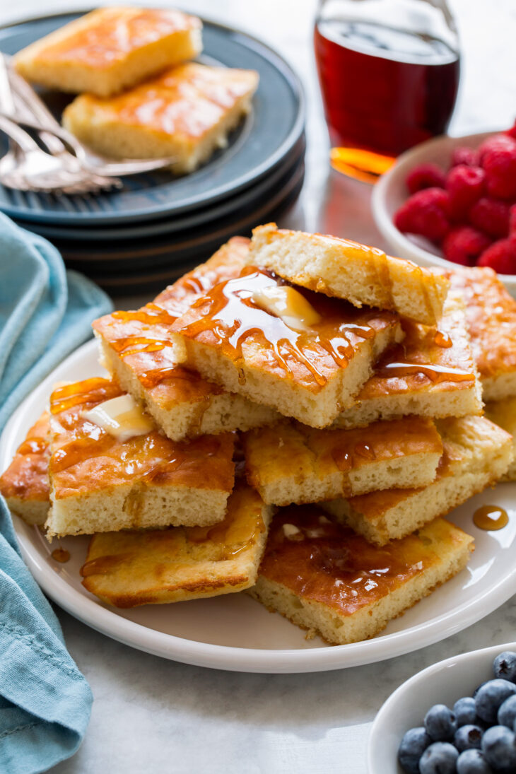 _*Sheet Pan Pancakes*_ /The easiest way to make a family size batch of pancakes! It's baked as one giant pancake in a hot oven then after finishing it's cut into individual squares. They're light and fluffy with a light buttermilk tang, and they have just a hint of sweetness allowing room for your favorite syrup finish./   #Butter #Buttermilk #Eggs #Flour #Sugar #VanillaExtract  Servings: 8 (24 squares, 3 per person) Ready in: 30 minutes Prep: 15 minutes Cook: 15 minutes  Ingredients:  8 Tbsp unsalted butter, melted, divided 2 1/2 cups (354g) all-purpose flour (scoop and level to measure), plus 1 Tbsp for dusting pan 1/4 cup (50g) granulated sugar 2 tsp baking powder 1 tsp baking soda 1 tsp salt 3 large eggs 2 1/2 cups low-fat buttermilk 1 tsp vanilla extract  Instructions: *1.* Preheat oven to 425 degrees. Brush an 18 by 13-inch rimmed baking sheet with 2 Tbsp melted butter, then dust baking sheet with 1 Tbsp flour and shake to coat. Set aside.  *2.* In a large mixing bowl whisk together flour, sugar, baking powder, baking soda and salt for 20 seconds. Make a well in center of mixture.  *3.* Crack eggs in a separate large mixing bowl. Whisk the eggs together then add in buttermilk and vanilla extract and mix.  *4.* While whisking pour in 5 Tbsp melted butter and mix well (it will clump up a little that's fine).  *5.* Pour buttermilk mixture into flour mixture and whisk until combined, batter should be slightly lumpy (don't over-mix or pancakes won't be as fluffy).  *6.* Right away pour batter into prepared baking sheet and spread into an even layer using a spatula.  *7.* Bake in preheated oven until baked through (a toothpick should come out clean), about 15 to 18 minutes (note that each oven browns differently if your oven didn't get a golden brown top you can remove then adjust oven rack closer to broiler, preheat broiler and let it toast just very briefly keeping a close eye on it).  *8.* Brush remaining 1 Tbsp melted butter over top, cut into squares and serve warm with maple syrup or other desired topping of choice.