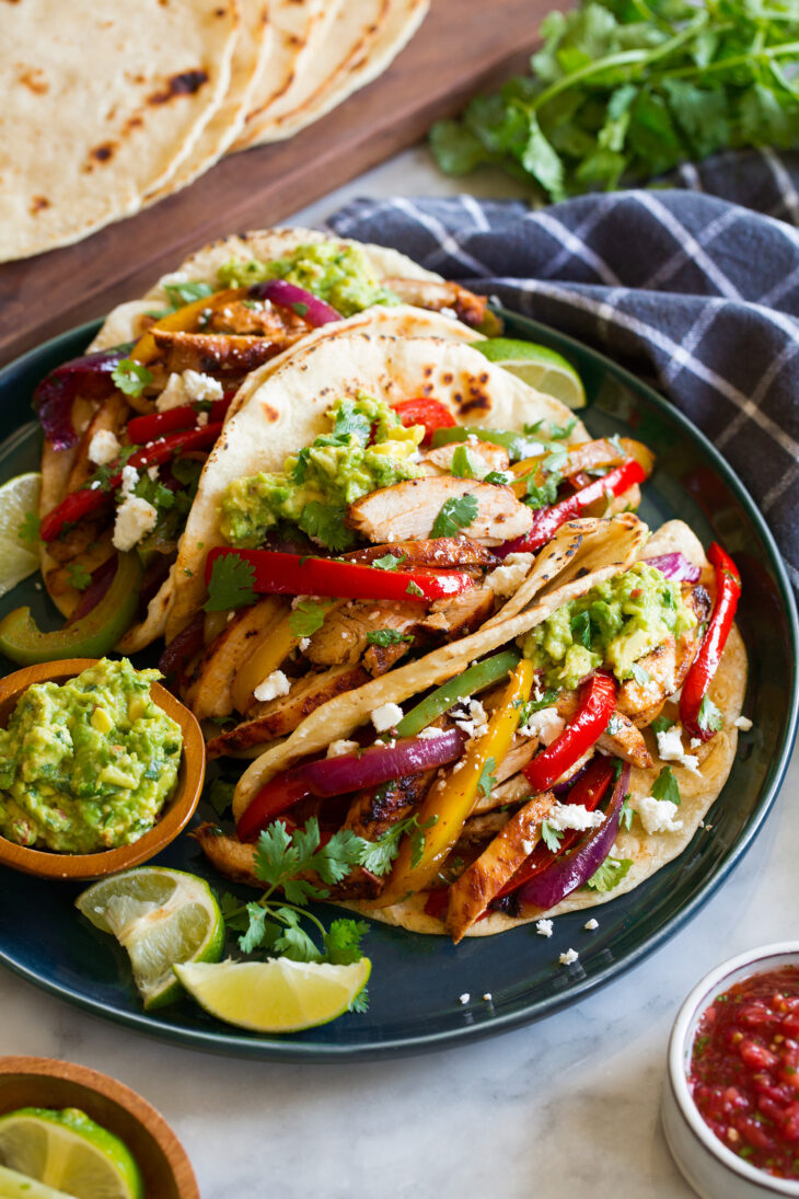 _*Chicken Fajitas*_ /One of the best dinners out there! This easy recipe is made with deliciously seasoned, marinated and pan seared chicken, a trio of fresh bell peppers and tender crisp onions. Easy to make and unbelievably delicious!/   #Healthy #MainDish #MexicanAndSouthwestern #Poultry #BellPepper #Chicken #ChiliPowder #Cilantro #Cumin #Garlic #Limes #OliveOil #Onions #Tortillas  Prep: 20 minutes. Cook: 15 minutes. Ready in: 2 hours 35 minutes.  Ingredients: 1: 1 1/2 lbs trimmed chicken thighs or chicken breasts*. 2: 5 Tbsp light olive oil divided. 3: 4 Tbsp fresh lime juice, divided. 4: 3 1/2 tsp minced garlic, divided. 5: 2 1/2 tsp chili powder, divided. 6: 2 tsp ground cumin, divided. 7: 1 jalapeno, seeded for less heat if desired, minced. 8: 1 1/4 tsp salt, more to taste. 9: 1 tsp freshly ground black pepper. 10: 3 medium bell peppers (preferably 1 red, yellow and green), seeded and sliced. 11: 1 medium red onion or yellow onion, sliced. 12: 3 Tbsp chopped fresh cilantro. 13: 8 (7-inch) flour tortillas, warmed, homemade are best if time allows. 14: Optional toppings, see notes.  Instructions: 1: In a medium non-reactive mixing bowl (such as glass or stainless steel), whisk together 3 Tbsp olive oil, 3 Tbsp lime juice, 2 tsp garlic, 2 tsp chili powder, 1 1/2 tsp cumin, jalapeno, salt and pepper. 2: Add chicken and toss well then submerge down into marinade. Cover and let marinate in refrigerator at least 1 hour and up to 6 hours. 3: Preheat a 12-inch cast iron pan over medium-high heat. Add 1 Tbsp olive oil then place chicken in skillet leaving space between pieces and cook until well browned of first side about 4 to 6 minutes (chicken thighs take near greater time). 4: Flip chicken and continue to cook until chicken registers 160 - 165 degrees on an instant read thermometer in center, about 4 to 6 minutes longer (chicken thighs take near greater time). If you find chicken is browning too quickly before cooking through you can reduce burner temperature slightly. 5: Transfer chicken to a cutting board, tent with foil and let rest 5 minutes before slicing. 6: Meanwhile, scrape up excess burnt bits from the skillet with a metal spatula if needed (you want some of those browned bits but not a lot of burnt black bits especially if you used thighs and had to cook longer). Add remaining 1 Tbsp oil to same cast iron skillet set over medium-high heat. 7: Add bell peppers and onions, season with salt and pepper to taste. Saute about 4 minutes, only tossing occasionally and scraping up browned bits from the bottom of pan. 8: Add remaining 1/2 tsp chili powder and 1/2 tsp cumin, 1 1/2 tsp garlic and saute until just tender crisp, about 2 minutes longer.** Pour in remaining 1 Tbsp lime juice and toss. 9: Return chicken to pan, toss in cilantro and serve warm over tortillas with optional toppings. Notes: *For chicken breasts you can use 4 (6 oz each) portions or 2 (12 oz each) portions halved through their thickness. Pound thicker areas of chicken breasts with the flat side of a meat mallet to even their thickness. For chicken thighs I recommend using about 4 oz. pieces, just trim the fat no flattening necessary. **If you still have stubborn browned bits at the bottom of the pan you can help release them by pouring in a splash of chicken broth or water, these bits adds lots of flavor to the dish. Nutrition estimate: based on two fajitas per person, using store-bought tortillas (homemade tortillas are about 50 calories extra each), and optional toppings not included. To make them healthier use corn tortillas instead of flour. I like to warm corn tortillas in skillet in a teaspoon of olive oil until lightly golden brown spots appear on each side. Topping Ideas (optional) Guacamole or sliced avocado Salsa or diced tomatoes Sour cream or Mexican crema Mexican hot sauce (such as Tapatio or Cholula) Cheese - queso fresco, Monterey jack, pepper jack, or cheddar  
