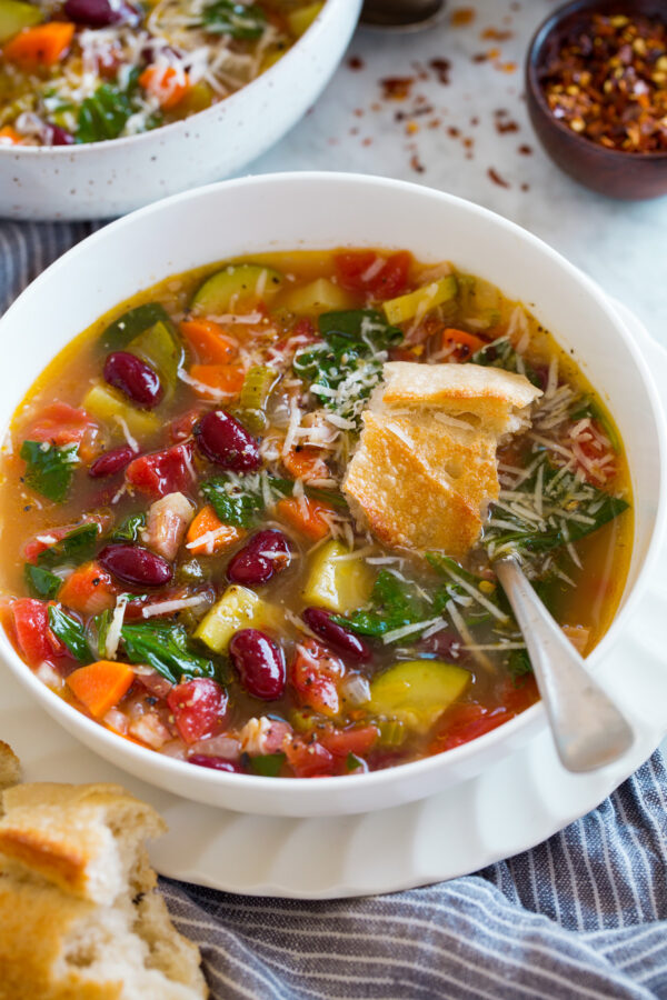_*Easy Minestrone Soup*_ /Our favorite Minestrone Soup recipe! It’s brimming with fresh vegetables, a savory broth, and you get an enticing flavor boost from a bit of pancetta. A simple soup that’s just what you need after a long chilly day./   #FallFaves #Healthy #PastaItalian #Soups #Carrots #Celery #ChickenBroth #Garlic #KidneyBeans #OliveOil #Pancetta #ParmesanCheese #Rosemary #Spinach #Tomatoes #YellowOnion #Zucchini  Prep: 15 minutes. Cook: 30 minutes. Ready in: 40 minutes.  Ingredients: 1: 4 oz. pancetta*, diced into 1/4-inch pieces. 2: 2 Tbsp extra virgin olive oil. 3: 1 1/2 cups chopped yellow onion (1 medium). 4: 3/4 cup chopped carrot (1 large). 5: 3/4 cup thin sliced celery (2 ribs). 6: 1 Tbsp minced garlic (3 cloves). 7: 4 cups low-sodium chicken broth or vegetable broth. 8: 1/2 cup water or more broth. 9: 1 (14.5 oz) can petite diced tomatoes. 10: 1 small zucchini, diced (1 cup). 11: 1 rosemary sprig. 12: 1 small parmesan rind (about 4-inches), plus shredded parmesan for serving. 13: Salt and freshly ground black pepper. 14: 2 cups (2 oz) fresh spinach, roughly chopped. 15: 1 (14.5 oz) can dark red kidney beans or cannellini beans, drained and rinsed. 16: Red pepper flakes, to taste (optional).  Instructions: 1: Heat pancetta with olive oil in a pot over medium heat. Cook until just lightly browned, about 4 - 5 minutes. 2: Add onion, carrot and celery and saute until starting to soften, about 7 minutes. 3: Add garlic and saute 1 minute longer. 4: Pour in broth, water, tomatoes, and add zucchini, rosemary, and parmesan rind. 5: Bring to a simmer over medium-high heat. Then reduce heat to medium-low, cover and simmer, stirring once halfway through, about 10 minutes total or until zucchini is tender. 6: Remove rosemary and parmesan rind. Season to taste with salt and pepper (you shouldn't need much salt, it's already fairly salty). 7: Stir in kidney beans and spinach and let heat through, about 30 seconds. For a brothier soup you can add in a little more broth to thin as desired. 8: Serve warm with shredded parmesan and red pepper flakes if desired. Notes: *This is an Italian pork. I buy it at the deli counter, Boar's Head brand is a good option. Ask for it thick cut, about 1/4-inch thick. Try it with other vegetables you may have on hand, minestrone is so versatile. Here are some good options (add more broth to thin and more fresh herbs to season as desired):  asparagus broccoli butternut squash cabbage carrots cauliflower celery eggplant fennel green beans kale mushrooms onions parsnips peas potatoes tomatoes yellow squash zucchini Other Herbs to Try Basil Marjoram Oregano Thyme Parsley  