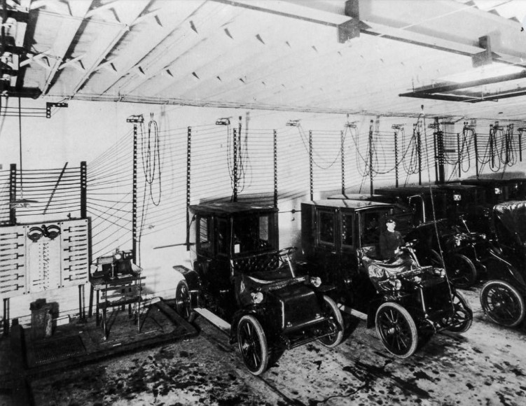 In 1909, electric vehicles (EVs) were not a futuristic concept—they were very much part of everyday urban life. During the early 20th century, electric cars were often more popular than gasoline-powered vehicles, particularly in cities, where their quiet operation, ease of driving, and lack of hand-cranking made them highly appealing. They were especially favoured by women and urban dwellers, who appreciated the convenience and cleanliness of electric propulsion. By 1912, nearly 40% of all American cars ran on electricity. The image from this period captures a rare glimpse of an early charging facility, complete with dozens of hanging cables and a large charging board, illustrating how electric vehicle infrastructure was already taking shape more than a century ago. These stations were vital, as EVs relied on lead-acid batteries that required regular recharging to remain functional. Companies like General Electric contributed to this burgeoning network, manufacturing public chargers that allowed city drivers to recharge their vehicles efficiently. Despite their initial popularity, electric cars began to decline in the 1920s. The emergence of inexpensive gasoline, the rapid improvement of internal combustion engines, and the expansion of paved road networks made petrol-powered cars more practical, especially for long-distance travel. Additionally, rural areas lacked sufficient electrification, limiting the reach and convenience of electric vehicles. Looking back at these early charging stations provides a fascinating perspective on the cyclical nature of technological adoption. Over a century ago, society was already experimenting with electric mobility, and today, as EVs experience a modern renaissance, it is striking to see the continuity of ideas. The image not only highlights the ingenuity of early 20th-century engineers and city planners but also serves as a reminder that the pursuit of sustainable transportation has deep historical roots, long before the current wave of innovation and environmental consciousness.